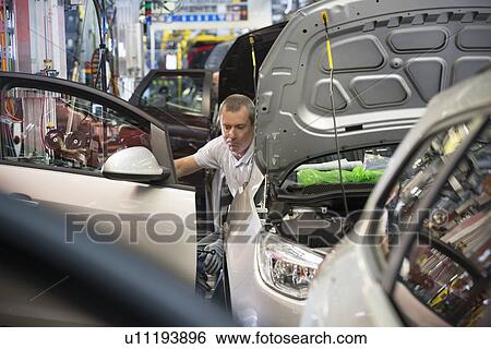 Stock Photograph - Worker fitting doors in car in car factory. Fotosearch