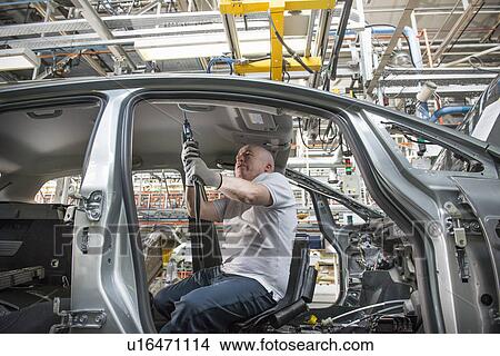 Worker fitting headliner in car in car factory View Large Photo Image Picture - Worker fitting headliner in car in car factory. Fotosearch