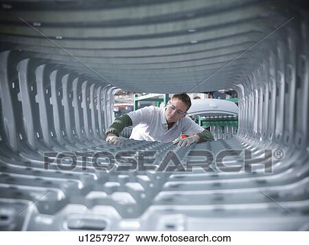 Stock Photo - Worker inspecting car body pressings in car factory. Fotosearch