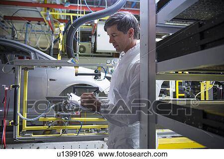 Worker inspecting car in car factory View Large Photo Image Stock Photograph - Worker inspecting car in car factory. Fotosearch