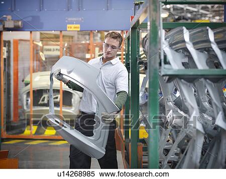 Stock Photography - Worker inspecting car parts in car factory. Fotosearch