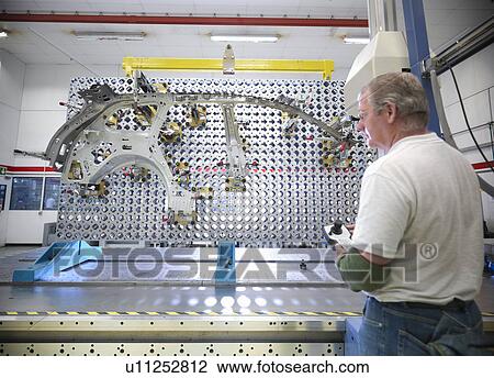 Stock Image - Worker inspecting measurement jig for car parts in car factory. Fotosearch