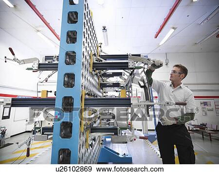 Stock Photo - Worker inspecting measurement jig for car parts in car factory. Fotosearch