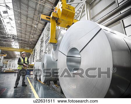 Worker operating crane with steel rolls in car factory View Large Photo Image Stock Image - Worker operating crane with steel rolls in car factory. Fotosearch