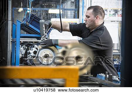 Stock Photo - Worker producing car parts in car factory. Fotosearch