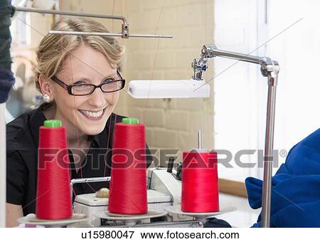 Stock Photo - Worker sewing fabric in garment factory. Fotosearch