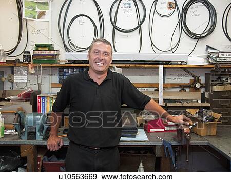 Worker smiling in workshop View Large Photo Image Stock Photo - Worker smiling in workshop. Fotosearch