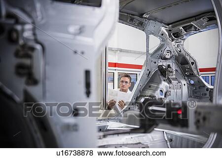 Stock Photo - Worker with car body on measuring machine in car factory. Fotosearch