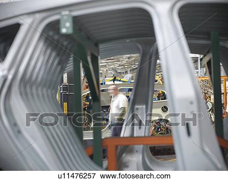 Stock Photo - Worker with car parts in car factory. Fotosearch