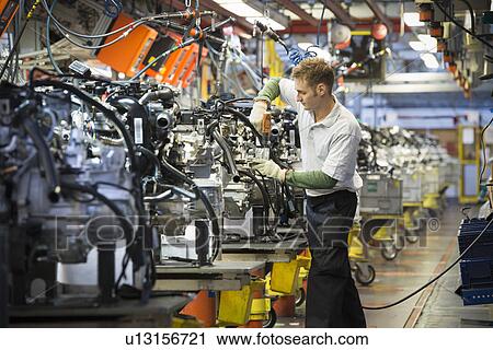 Worker with engines on production line in car factory View Large Photo Image Stock Image - Worker with engines on production line in car factory. Fotosearch