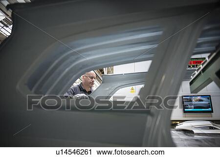 Worker with pressed steel car parts in car factory View Large Photo Image Stock Image - Worker with pressed steel car parts in car factory. Fotosearch