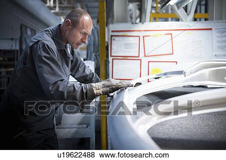 Worker with pressed steel car parts in car factory View Large Photo Image Stock Photo - Worker with pressed steel car parts in car factory. Fotosearch