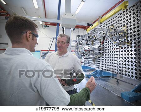 Stock Photo - Workers discussing measurement jig for car parts in car factory. Fotosearch