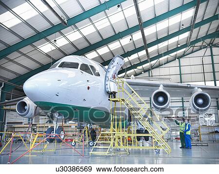 Workers inspecting jet aircraft in hangar View Large Photo Image Stock Photo - Workers inspecting jet aircraft in hangar. Fotosearch
