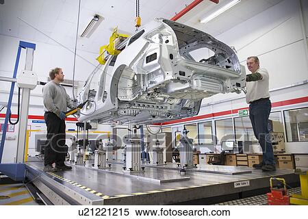 Stock Photography - Workers placing car body on measuring machine in car factory. Fotosearch