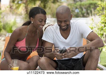 Stock Image - African American couple socializing around pool. Fotosearch