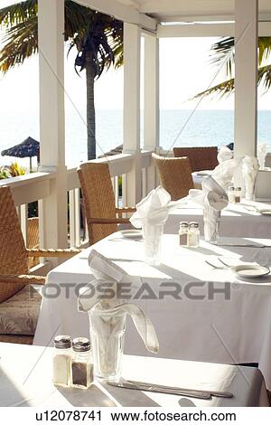 Stock Image - Beach resort restaurant table settings. Fotosearch
