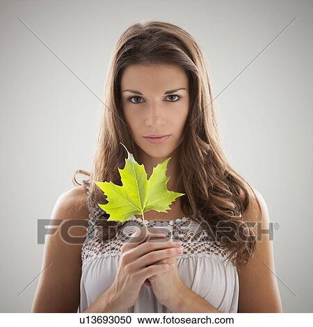 Stock Image - Beautiful woman holding green sycamore leaf. Fotosearch