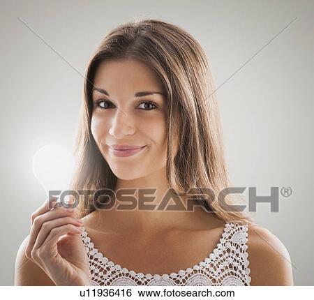 Beautiful woman holding light bulb View Large Photo Image Stock Photograph - Beautiful woman holding light bulb. Fotosearch