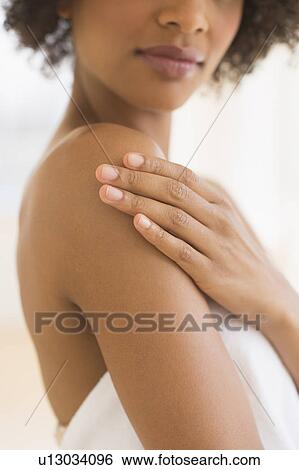 Stock Photograph - Beauty shot of woman touching shoulder, studio shot. Fotosearch