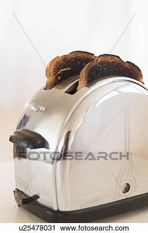 Stock Image - Burnt toasts in toaster. Fotosearch