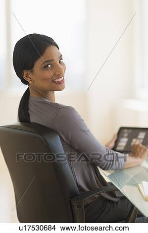 Picture - Businesswoman using digital tablet in office. Fotosearch