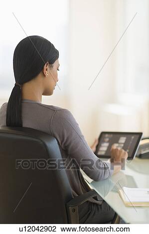 Stock Image - Businesswoman using digital tablet in office. Fotosearch