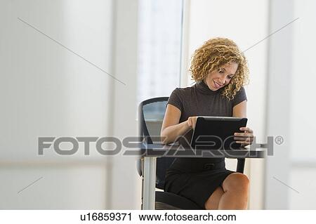 Stock Image - Businesswoman working at desk in office. Fotosearch