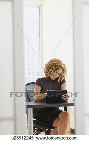 Stock Photography - Businesswoman working at desk in office. Fotosearch