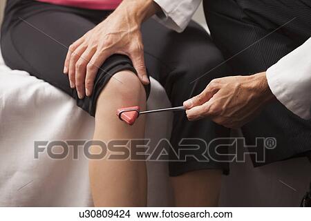 Picture - Close-up of doctor checking knee reflexes. Fotosearch