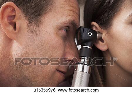 Stock Photograph - Close-up of doctor doing ear exam with Otoscope. Fotosearch