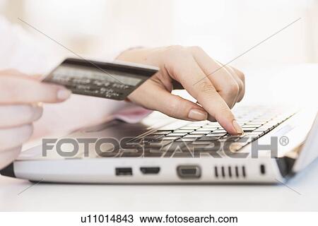 Stock Image - Close up of woman's hand doing online banking with laptop. Fotosearch