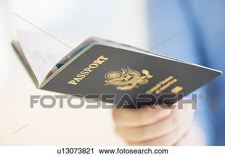 Stock Image - Close up of woman's hand holding open passport. Fotosearch