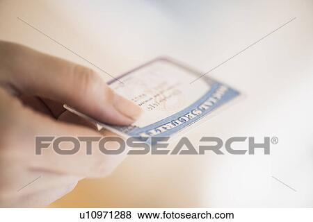 Stock Photo - Close up of woman's hand holding social security card. Fotosearch