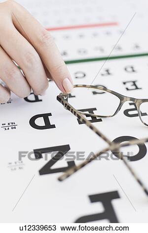 Close up of woman's hands holding glasses above eye chart, studio shot View Large Photo Image Stock Image - Close up of woman's hands holding glasses above eye chart, studio shot. Fotosearch