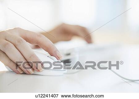 Stock Photo - Close up of woman's hands using computer keyboard and computer mouse. Fotosearch