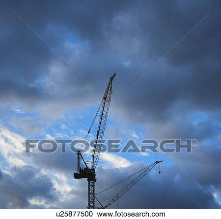 Construction cranes on cloudy sky View Large Photo Image Stock Image - Construction cranes on cloudy sky. Fotosearch