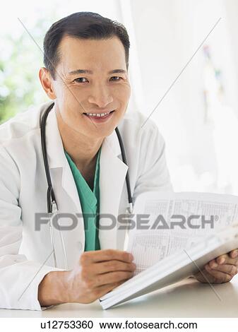 Stock Image - Doctor examining medical records. Fotosearch