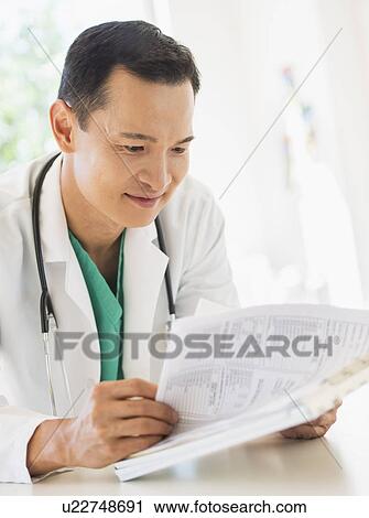 Stock Image - Doctor examining medical records. Fotosearch