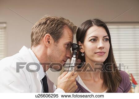 Stock Photography - Doctor performing hearing test with Otoscope. Fotosearch