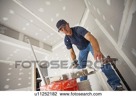 Drywall worker adding drywall mud to his banjo View Large Photo Image Stock Image - Drywall worker adding drywall mud to his banjo. Fotosearch