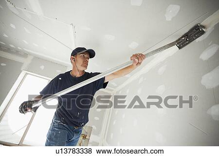 Drywall worker applying tape to corner between wall and ceiling View Large Photo Image Stock Photo - Drywall worker applying tape to corner between wall and ceiling. Fotosearch