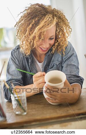 Picture - Female artist painting on ceramics in studio. Fotosearch