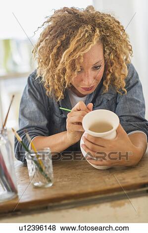 Stock Photo - Female artist painting on ceramics in studio. Fotosearch