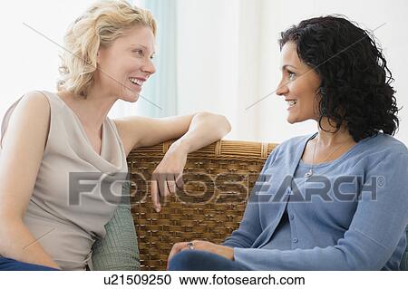 Female friends sitting on sofa and talking View Large Photo Image Stock Image - Female friends sitting on sofa and talking. Fotosearch