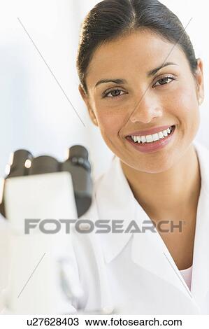Stock Image - Female scientist looking through microscope. Fotosearch