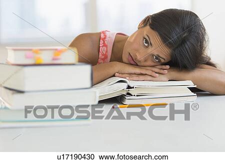 Stock Image - Female student leaning on books. Fotosearch