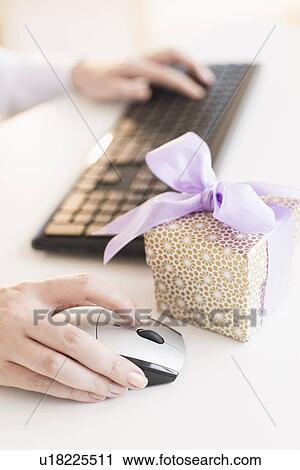 Gift box on desk next to woman using computer View Large Photo Image Stock Image - Gift box on desk next to woman using computer. Fotosearch