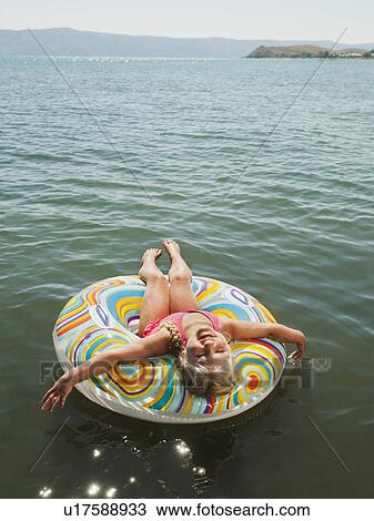 Girl (4-5) floating on water on inflatable ring and laughing View Large Photo Image Stock Image - Girl (4-5) floating on water on inflatable ring and laughing. Fotosearch