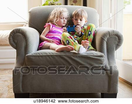 Girl and boy sitting on armchair and playing video game View Large Photo Image Stock Image - Girl and boy sitting on armchair and playing video game. Fotosearch
